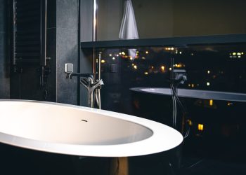 The interior of a modern bathroom with a window overlooking the night city, copy space.